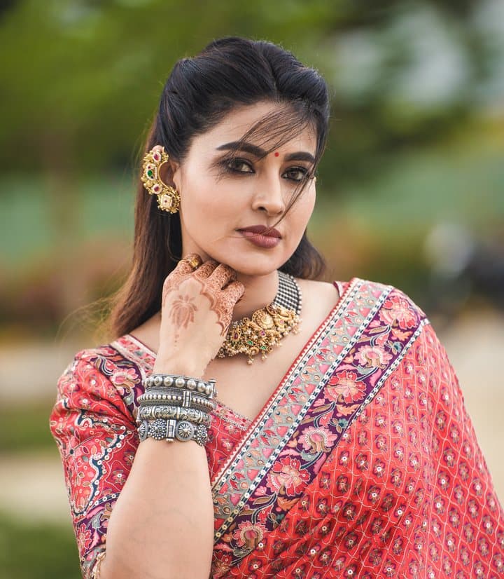 Model in a coral-pink saree with an embroidered border