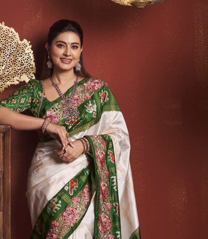 Model in an ivory silk saree with a green floral border